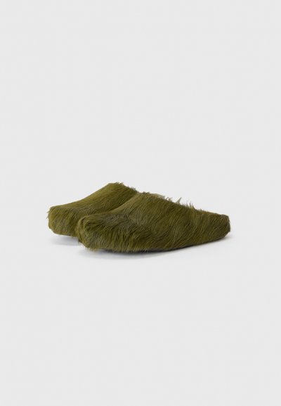 Olivgröna fluffiga träskor med rundad form, som har en texturerad, hårig yta och en enkel design. Inga synliga detaljer eller accenter.