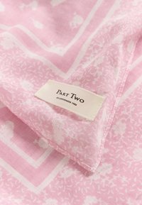 Tessuto rosa a fantasia con motivi floreali e bordi geometrici. Un'etichetta di stoffa riporta "Part Two, Est. Copenhagen 1986." Texture morbida e leggera.