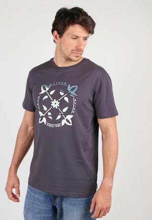 T-shirt en coton gris à manches courtes avec un motif floral circulaire en bleu et blanc. Encolure ronde classique, coupe décontractée.
