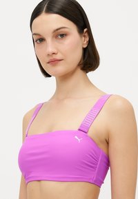 Ροζ αθλητικό σουτιέν φτιαγμένο από λείο υλικό, με φαρδιές τιράντες που διαθέτουν λογότυπα και εφαρμοστό σχέδιο. Δεν υπάρχουν διακοσμήσεις.