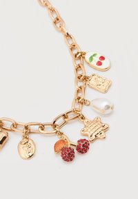 Bracelet chaîne en or avec des breloques comprenant des cerises incrustées de bijoux rouges, une perle, une étoile, une rose et un motif de cerise sur émail blanc.