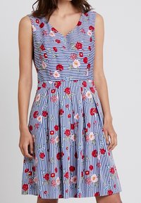 Vestido floral sin mangas con escote en V. Rayas azules y blancas, adornado con flores rojas, rosas y azules. Falda acampanada con pliegues.