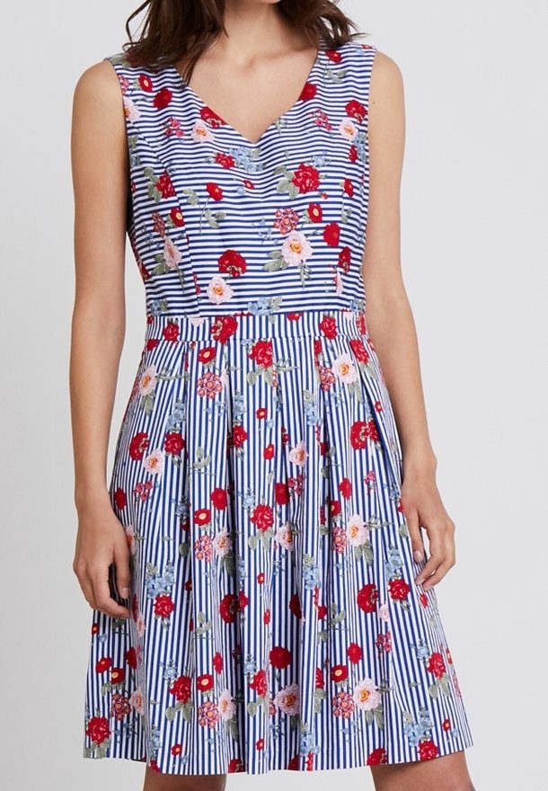 Vestido floral sin mangas con escote en V. Rayas azules y blancas, adornado con flores rojas, rosas y azules. Falda acampanada con pliegues.