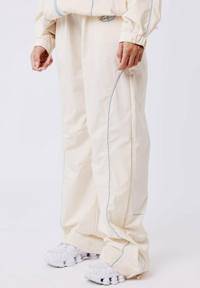 Beige cargobroek met blauwe piping, elastische boorden, zijzakken en een relaxte pasvorm. Draag het met witte, gestructureerde sneakers.