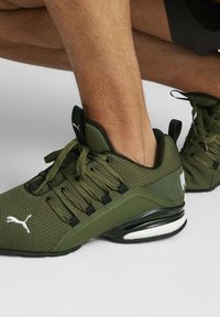 Groene mesh sportschoenen met zwarte accenten, met een gevoerde zool, dikke veters en een wit logo op de zijkant.