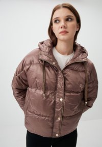 Gepolsterte Jacke in hellbraun mit glänzender Oberfläche, ausgestattet mit Kapuze, Kordelzug, Schmetterlingsstickerei und Druckknopfverschluss.