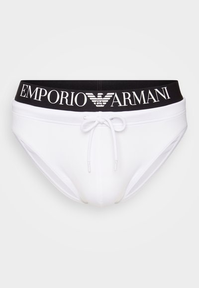 Bele kopalne hlačke z črnim elastičnim pasom, na katerem je v belem napisan "EMPORIO ARMANI". Vključujejo detajl vezanja spredaj. Gladka tkanina.