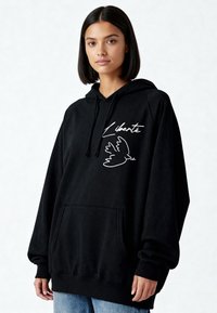Sweat à capuche noir en tissu doux. Il comprend une poche avant, un texte blanc brodé "Liberté" et un motif de colombe. Coupe décontractée.