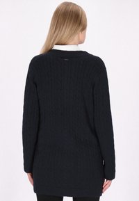 Maglione blu navy a maglia cable con maniche lunghe, scollatura rotonda e vestibilità morbida, caratterizzato da una piccola etichetta con logo sul retro.