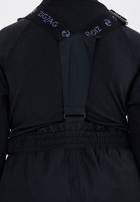 Vue arrière d'un pantalon de neige noir avec une taille élastique et des bretelles ajustables avec la marque ZigZag sur un t-shirt noir à manches longues.