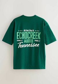Tricou verde cu mânecă scurtă, cu text alb și verde deschis care scrie "185 Red Clay St Echo Creek Audio Tennessee" pe spate.