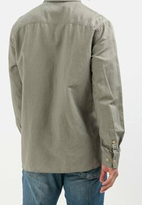 Overhemd met lange mouwen in licht olijfgroene stof, voorzien van een knoopmanchet, rechte snit en een subtiele textuur aan de achterkant.