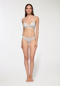 Set di bralette e slip in cotone grigio chiaro. La bralette presenta un design con fronte intrecciato e spalline sottili regolabili. Texture morbida e liscia.