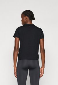 Juodas trumpomis rankovėmis marškinėliai, pagaminti iš minkštos medvilnės su apvaliu kaklu. Siūlo laisvą prigludimą ir švelnią tekstūrą, turintys minimalų dizaino detalių skaičių.