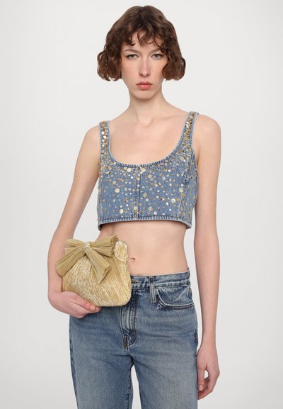 Denim crop topp med paljettdekorasjoner, kombinert med en teksturert gullveske med sløyfedetalj og lås.