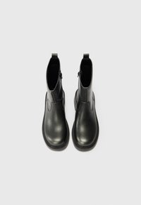 Black ankle boots with a smooth leather finish, zip closure on the side, and a rounded toe. Sturdy rubber sole with subtle tread details.