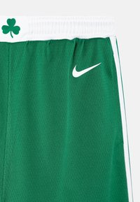 Zielone szorty sportowe z teksturowanej tkaniny, z białym pasem w talii, bocznymi paskami oraz białym logo Nike z akcentem w kształcie koniczyny.