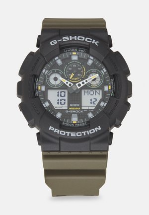 G-Shock digital klokke med svart og olivengrønn gummirem. Har flere klokker, digitalt display og fet hvit tekst. Støtsikker design.