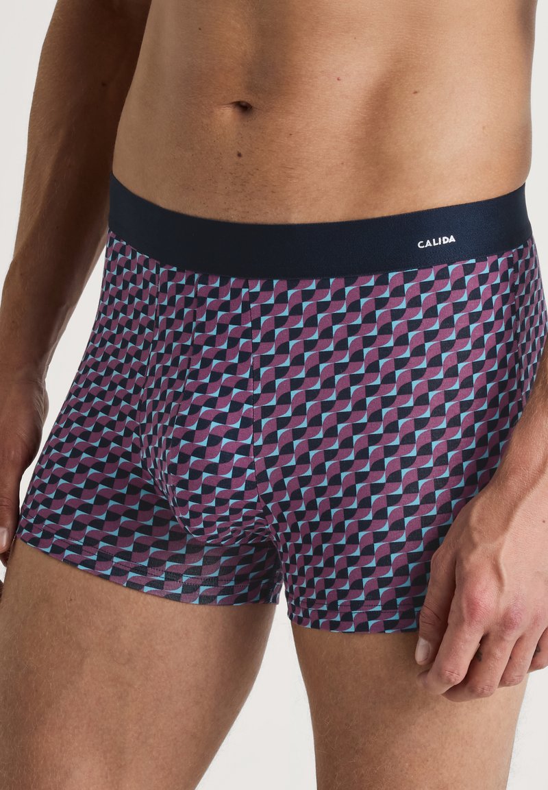Heren boxershorts in een geometrisch patroon van paars, blauw en zwart. Beschikt over een marineblauwe elastische tailleband met het label "CALIDA".
