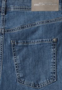 Modré džíny z denimu s kapsou na zadní straně a viditelným šitím. Na límci je šedá značka. Hladká textura, neformální design.