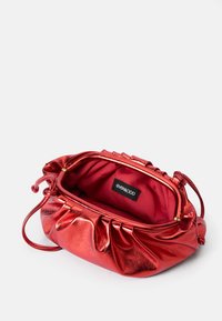 Red metallic handbag with a gathered design; features a soft textured red lining and a brand label inside. Adjustable shoulder strap included.
