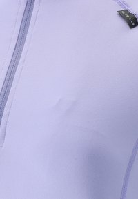 Hellpurpurnes Sportoberteil aus elastischem Stoff, mit einem halben Reißverschluss und strukturiertem Material, das sichtbare Nähte aufweist.