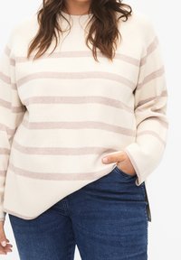 Maglione beige a righe realizzato in materiale morbido, con strisce marrone chiaro, scollo rotondo e una vestibilità comoda con spacchi laterali.