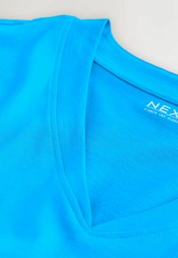 Maglietta a V di un azzurro brillante stesa, che mostra la texture liscia del tessuto e i dettagli di cuciture pulite intorno allo scollo.