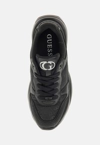 Zapatillas negras con parte superior texturizada, diseño de cordones, suela de goma y un acento de logo prominente en la lengua.