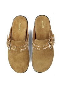 Zoccoli in suede marrone con una fascia intrecciata e una fibbia in tonalità oro sulla soletta, suola piatta e una finitura soft al tatto.