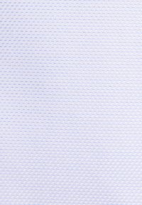 Gros plan d'un tissu blanc texturé avec un petit motif géométrique bleu et blanc qui se répète.