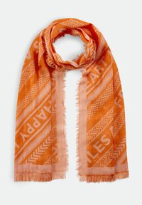 Écharpe orange à bords frangés avec des motifs géométriques et les mots « HAPPY », « HEART » et « SMILES » dans différentes nuances d'orange.