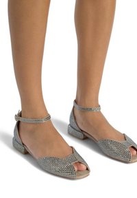 Zilveren sandalen met een open teen, versierd met kleine rhinestones, voorzien van een dunne enkelband en een lage vierkante hak. Gladde textuur.