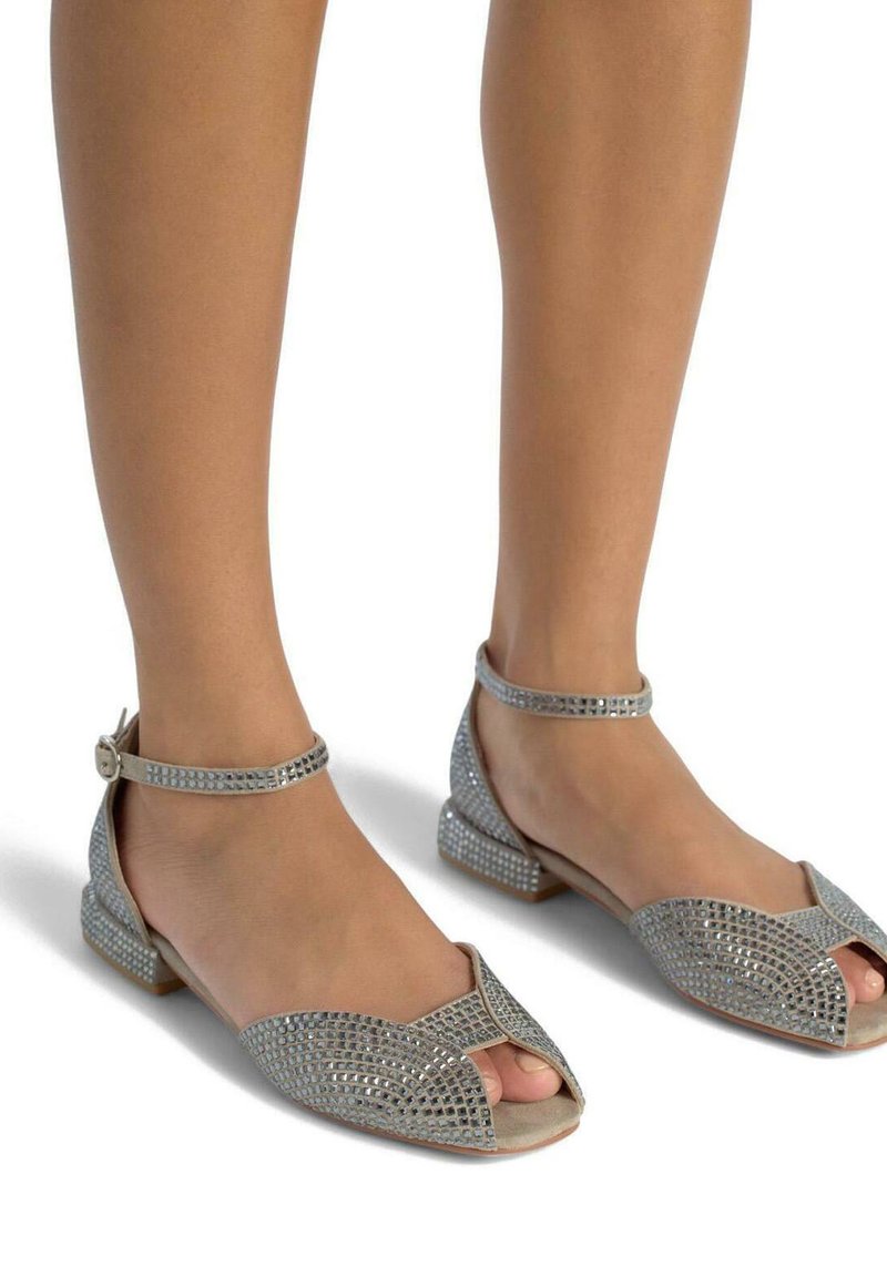 Zilveren sandalen met een open teen, versierd met kleine rhinestones, voorzien van een dunne enkelband en een lage vierkante hak. Gladde textuur.