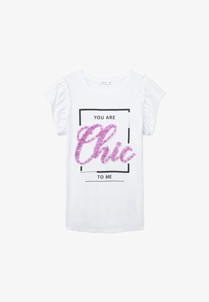 T-shirt bianco a maniche corte con maniche arricciate; presenta un design grafico con paillette rosa e viola che formano la parola "Chic" all'interno di un rettangolo.