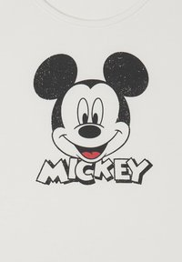 Viso sorridente di Topolino in bianco e nero con lingua rossa, sopra un testo in grassetto e usurato che legge "MICKEY" su tessuto bianco.