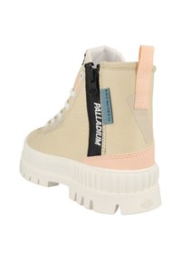 Beige high-top sneaker with a white chunky sole, black zipper, pastel pink accents, and reinforced eyelets. Features logo detailing and loop tab.
