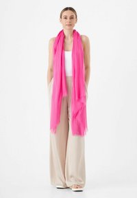Roze chiffon sjaal met een lichtgewicht, luchtig ontwerp en rafelige randen, casual om de nek gedrapeerd, gecombineerd met beige wijde broekspijpen.