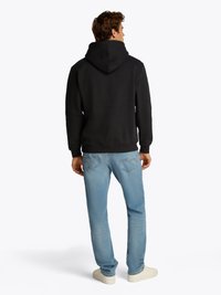 Svart hettegenser kombinert med lyseblå jeans. Hettegenseren har en hevet krage, mens jeansene har en bleket tekstur.
