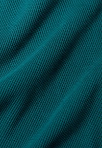 Téglalap alakú, texturált teal színű szövet, bordázott mintázattal, kiemelkedő és mélyebb vonalakkal, amelyek hullámszerű hatást keltenek. Puha és könnyű anyag.