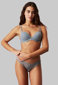 Gray lace-trimmed bra and matching thong, featuring smooth fabric, adjustable straps, and scalloped lace detailing.