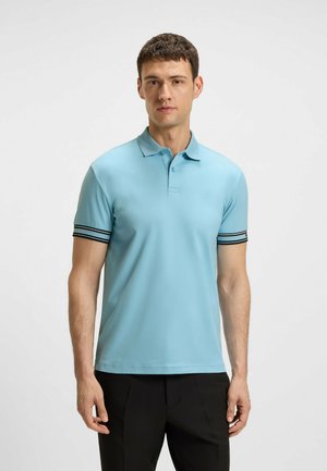 Hellblaues Polohemd mit Kragen und kurzen Ärmeln, das mit schwarz-weißen Streifen verziert ist, aus glattem Stoff gefertigt und kombiniert mit schwarzen Hosen.