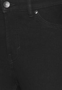 Jeans de mezclilla negra con una textura suave, que cuentan con un clásico diseño de 5 bolsillos, costuras en contraste y herrajes metálicos en la cintura.