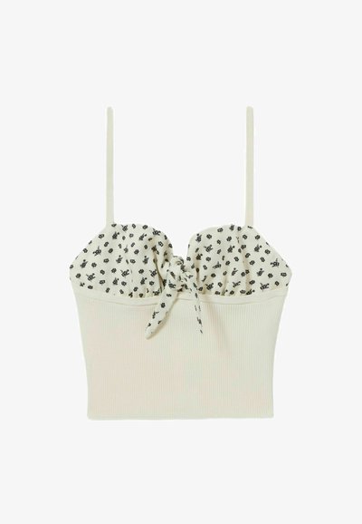 Crop top blanc à côtes avec un buste froncé imprimé floral et un détail noué au centre. Fines bretelles sur les épaules.