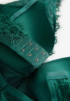Emerald green lace bra with sheer accents, soft fabric, delicate trim, and a multi-hook closure featuring copper-colored hardware.