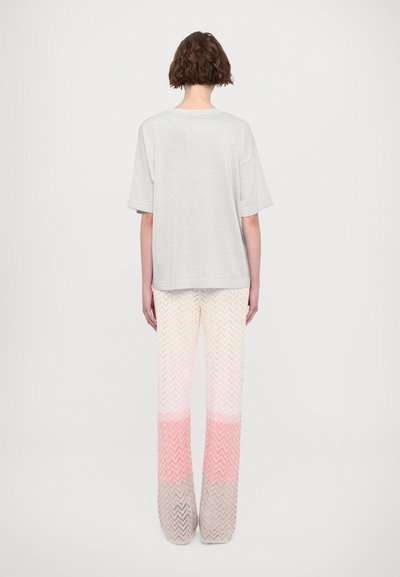 Gray, short-sleeve t-shirt paired with wide-leg pants featuring a zigzag pattern in gradient shades of white, pink, and beige.