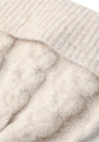 K�äsinkudottu villa kangas pehmeässä beigemassa, jossa on uritettu pinta ja hienot, pörröiset yksityiskohdat kauttaaltaan.