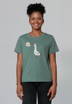 Grünes Baumwoll-T-Shirt mit einem Cartoon-Möwe-Design und einer Sprechblase, die "MAMA!" sagt, auf der Vorderseite. Kurze Ärmel und runder Ausschnitt.