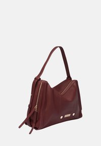 Bordeaux lederen handtas met een gladde textuur, schuin ontwerp, twee ritscompartimenten en accenten in goudkleurige hardware.