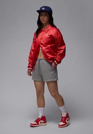 Red satin jacket, gray shorts, red and white sneakers. The jacket has a collar and drawstrings at the sleeves; the shorts feature a logo.